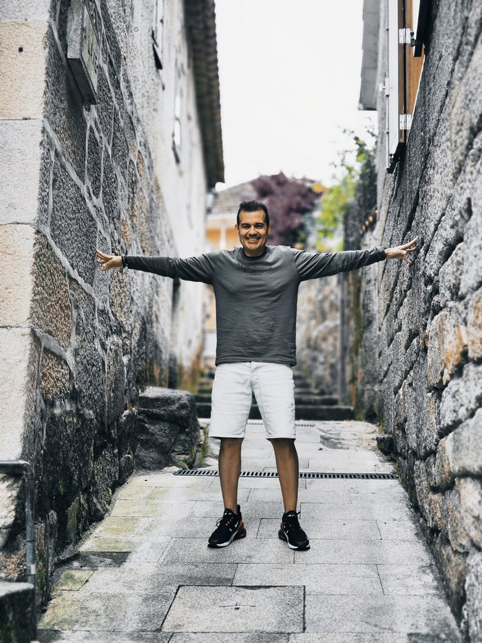 Fundador de SportBeat sonriendo con los brazos abiertos en una calle empedrada
